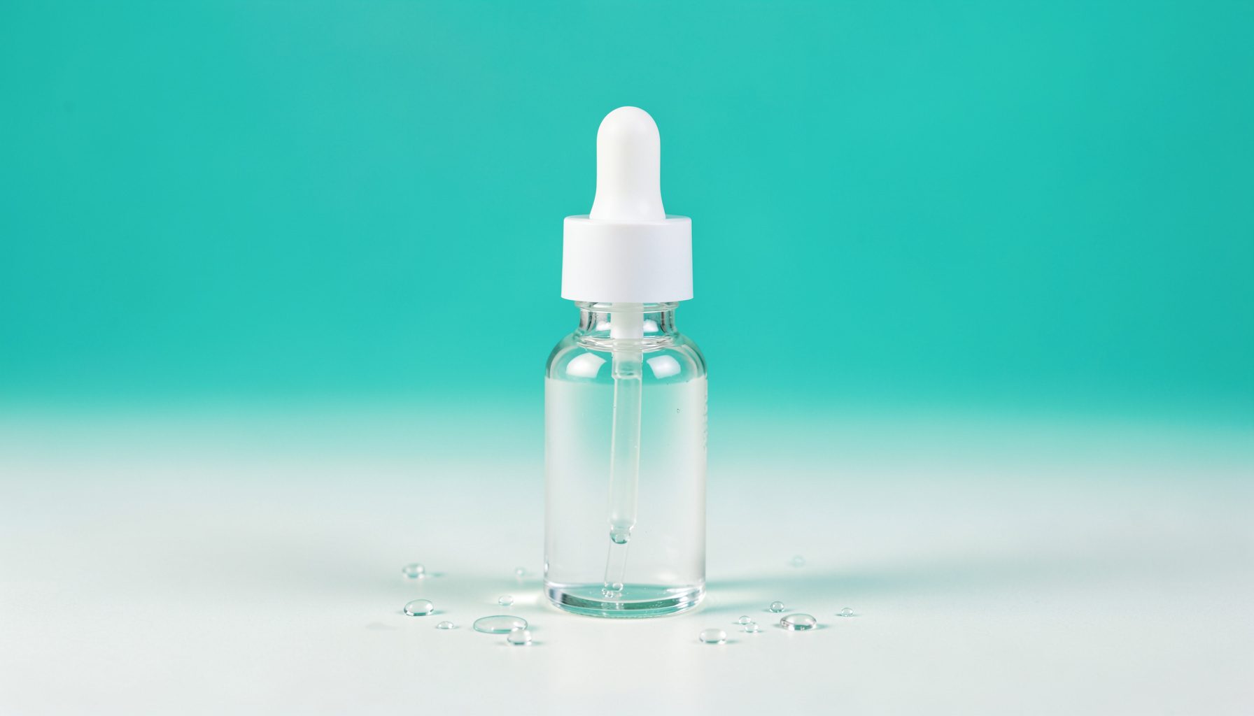 A softly lit studio still life of a clear glass serum dropper bottle standing on a pale seamless backdrop, surrounded by delicate water droplets, in calm teal and white tones with a clean, wellness-focused mood